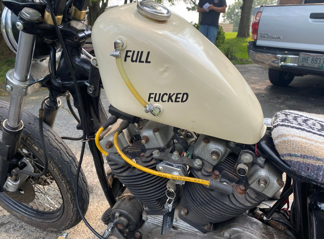 Motorcycle with a cream-colored fuel tank displaying the word 'FULL' and 'FUCKED'.