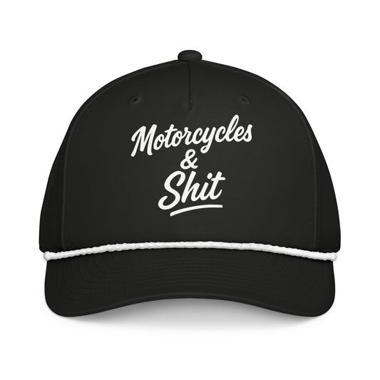 Black 'Motorcycles and Shit' trucker hat by Highway Division, styled with biker streetwear, worn by a rider standing next to a custom Harley-Davidson motorcycle.