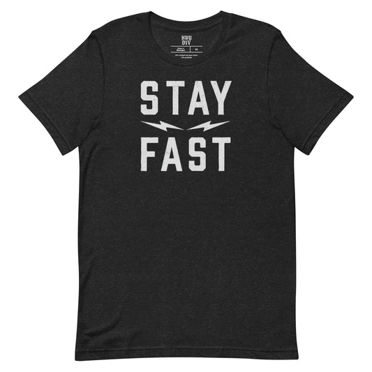 A black short-sleeve t-shirt from Highway Division, displayed flat against a neutral background. The shirt features a bold, minimalist front print in large, capitalized white letters that read “STAY FAST,” centered across the chest. The font is strong and modern, evoking speed and motion, with no other visible graphics, branding, or embellishments on the front or sleeves. The material appears soft and lightweight, likely 100% cotton, with a regular fit and classic crew neckline. There are no visible prints