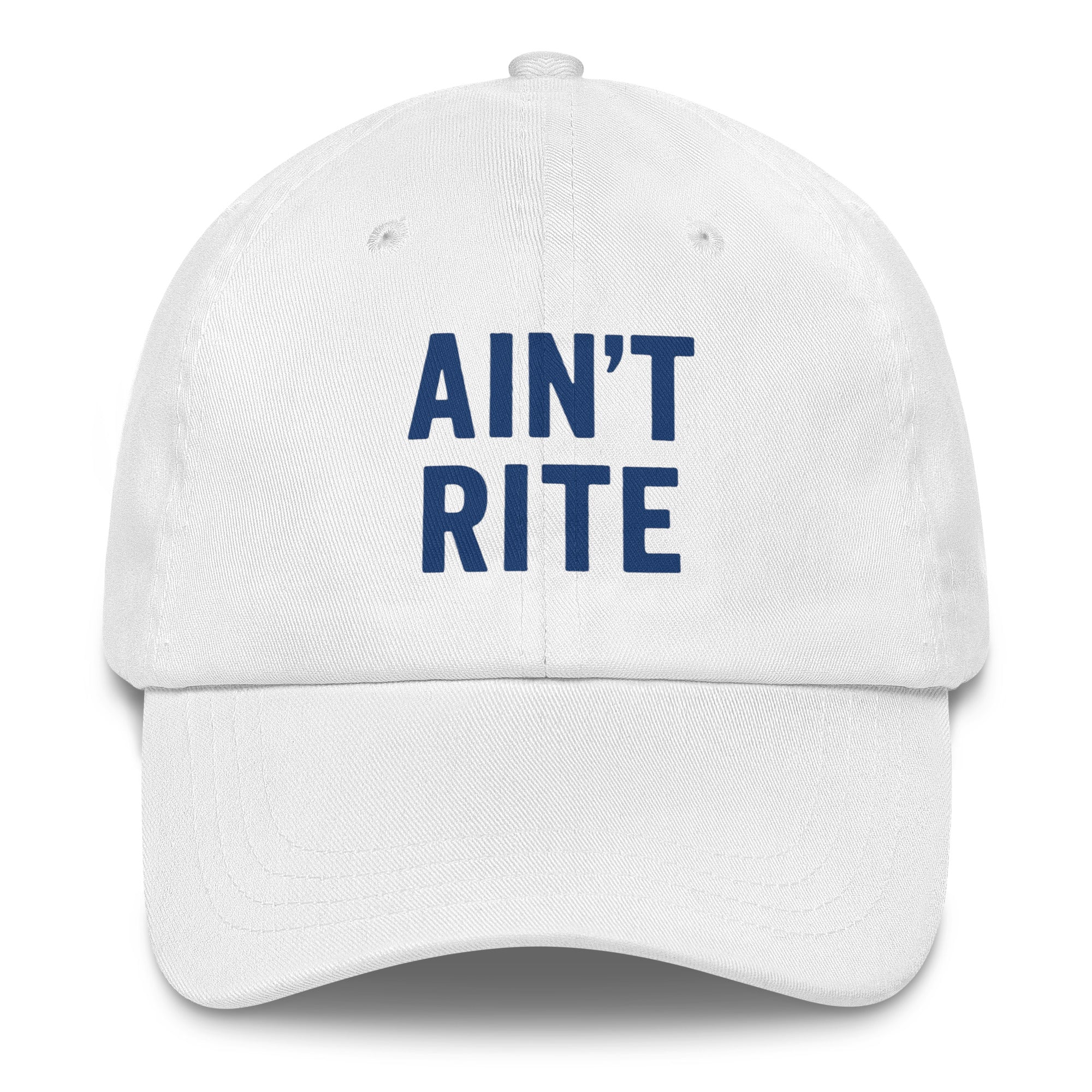 A stylish white hat from Highway Division is shown either resting on a clean surface or worn by a model in an urban setting. The hat features bold black embroidery on the front panel that reads “AIN’T RITE” in all capital letters, using a heavy, block-style font that stands out sharply against the crisp white background. The design is intentionally raw and rebellious, capturing the brand’s signature anti-conformist message. The hat has a classic 6-panel construction with a gently curved brim.