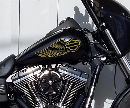 Close-up of gold leaf Harley-Davidsn wing tank decals by Highway Division, hand-applied for a custom look on a black fuel tank.