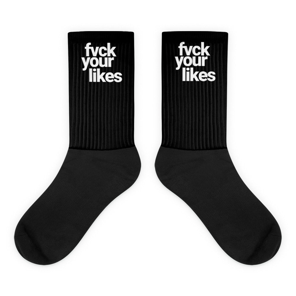 pair of black Highway Division socks with bold white woven text reading “FUCK YOUR LIKES” across the upper cuff. The socks have a ribbed texture, reinforced heel and toe, and a rebellious streetwear aesthetic.