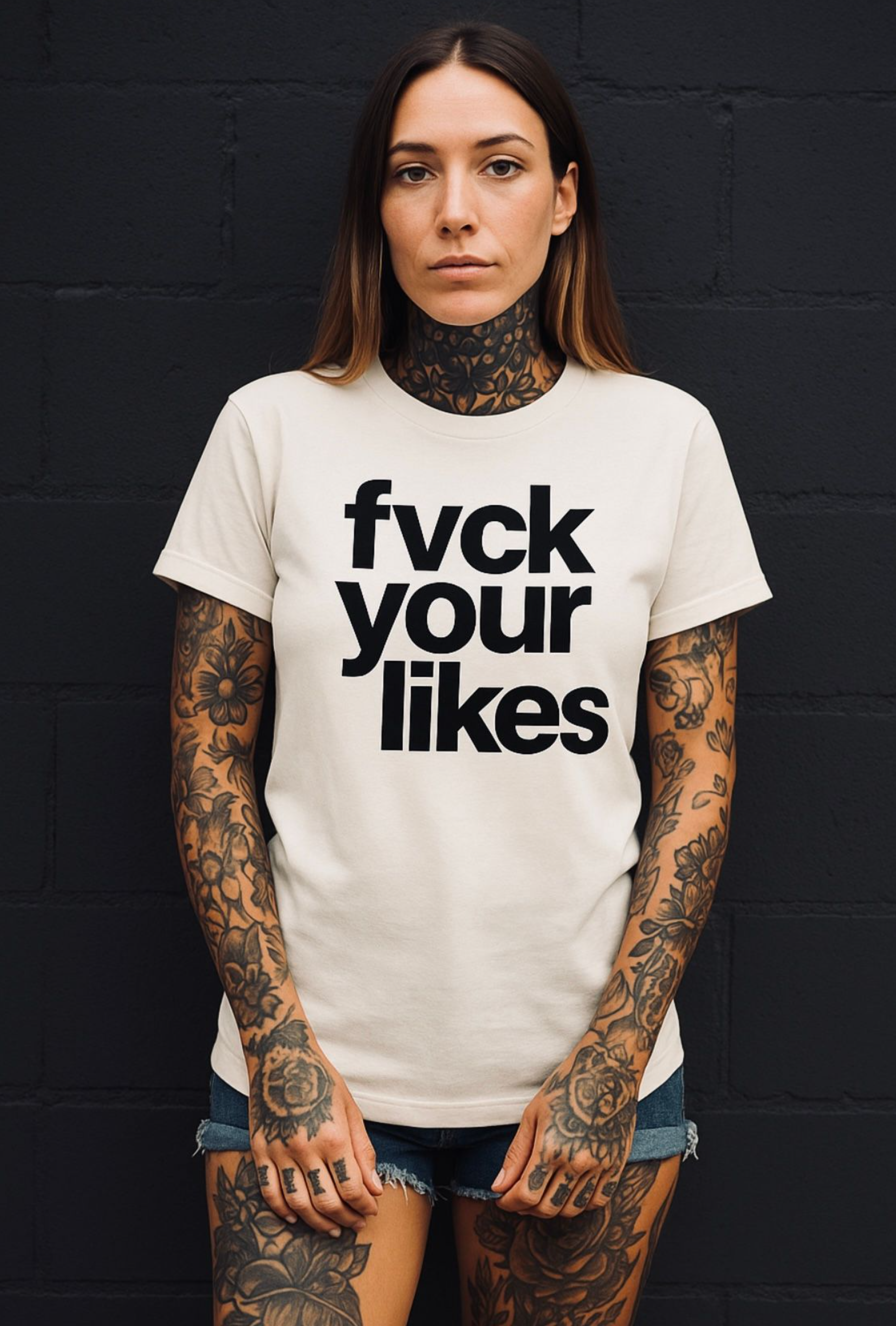Person wearing a white t-shirt with 'fuck your likes' text against a black brick wall.